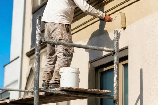 Painter on scaffolding repainting smooth stucco in Wilshire Montana